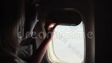 女人打开飞机上窗户的窗帘。 开始旅行的概念